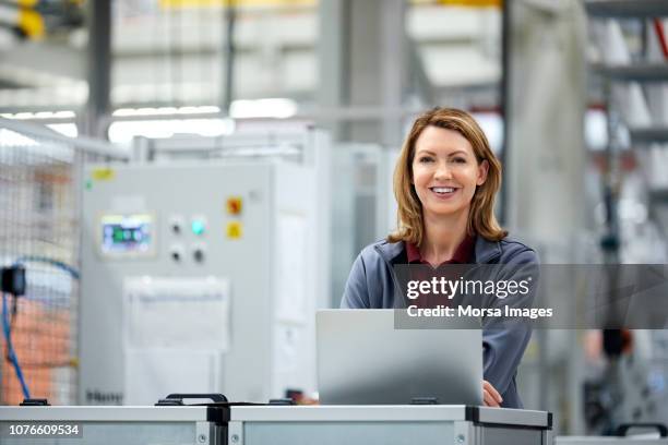 lächelnd ingenieurin mit laptop im automobilwerk - factory engineer woman stock-fotos und bilder