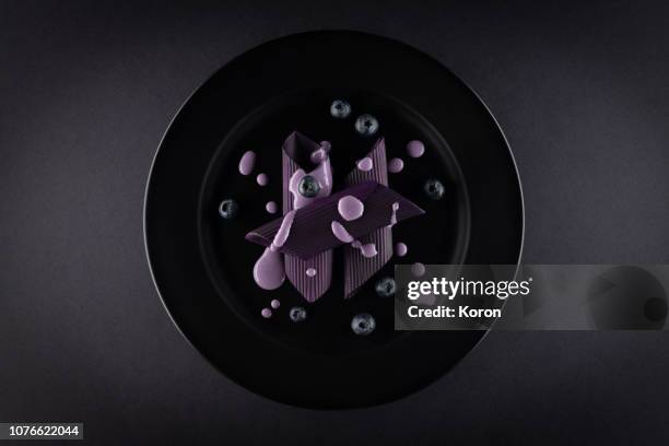 black and purple pasta on a black plate with blueberries - squid ink pasta stock pictures, royalty-free photos & images