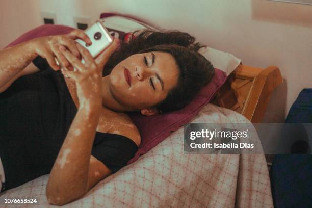 woman using her phone in bed - showus phone stock pictures, royalty-free photos & images