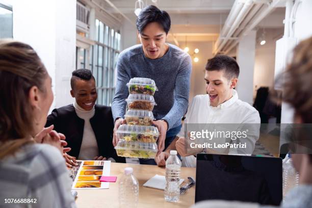 giovane squadra che mangia in ufficio alla pausa pranzo - pranzo foto e immagini stock