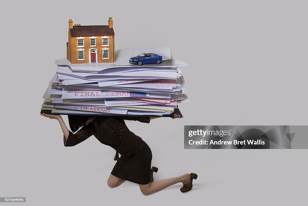 Woman carrying a stack of bills, house and a car