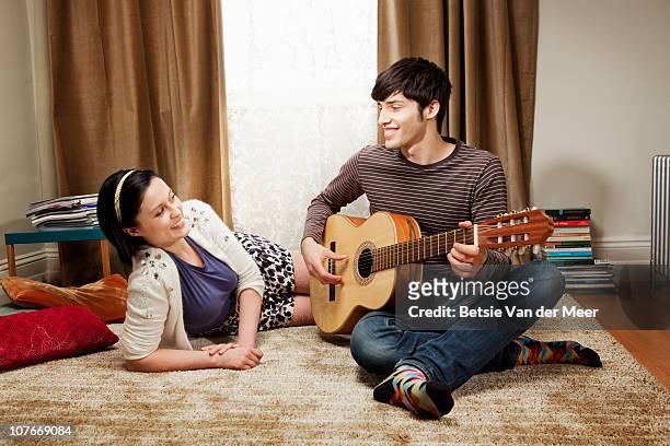 young man playing gitar for girlfriend. - seduzione foto e immagini stock