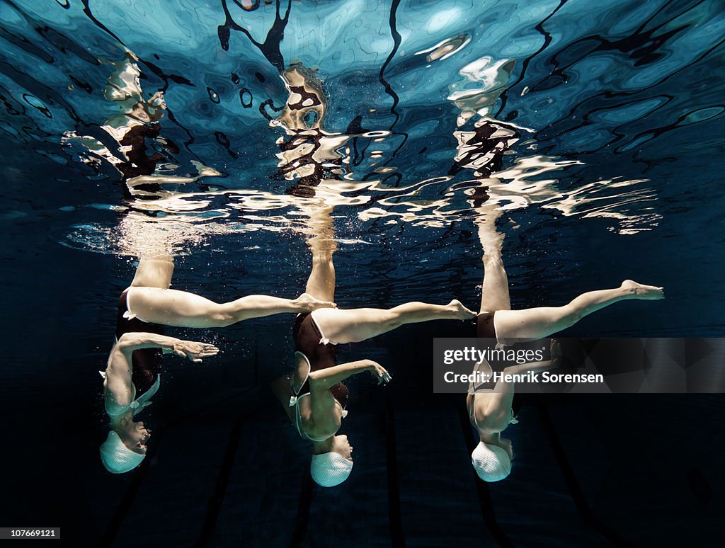 Three synchronised swimmers in formation