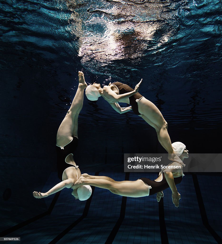 Three synchronised swimmers in formation