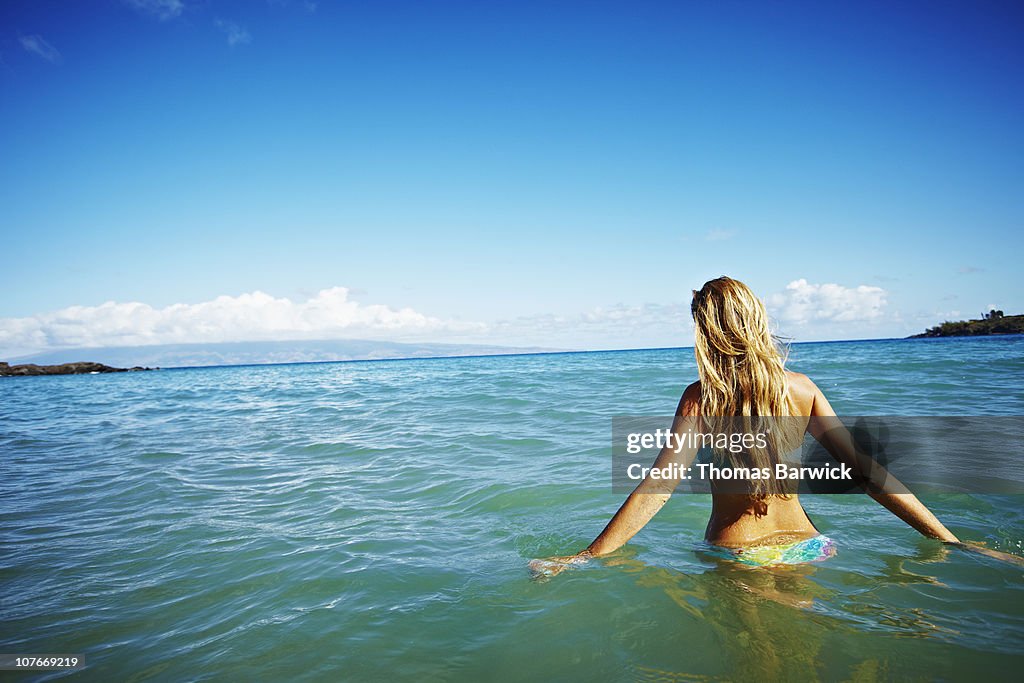 Woman walking out into ocean rear view