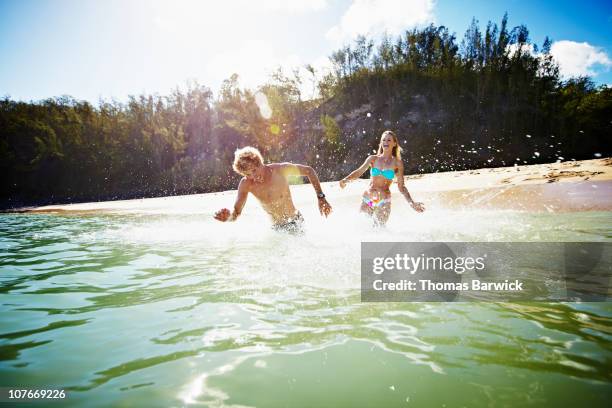 couple running out into water laughing - hawaii fun fotografías e imágenes de stock