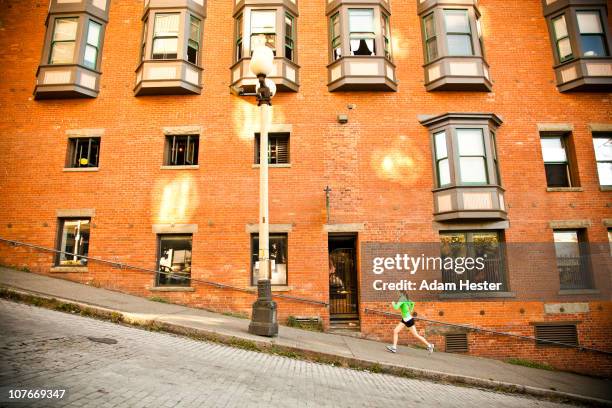 a young women running up a hill in an urban area. - training center stock pictures, royalty-free photos & images