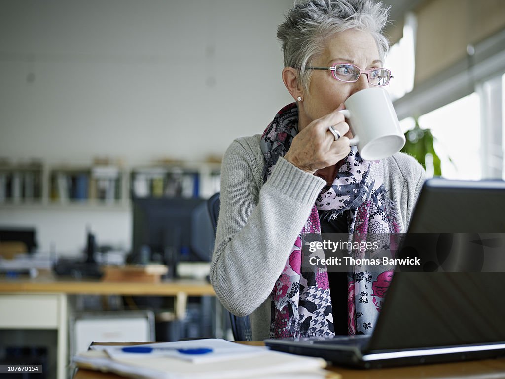 Businesswoman sitting in office drinking coffee