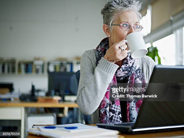 businesswoman sitting in office drinking coffee - baby boomer stock pictures, royalty-free photos & images