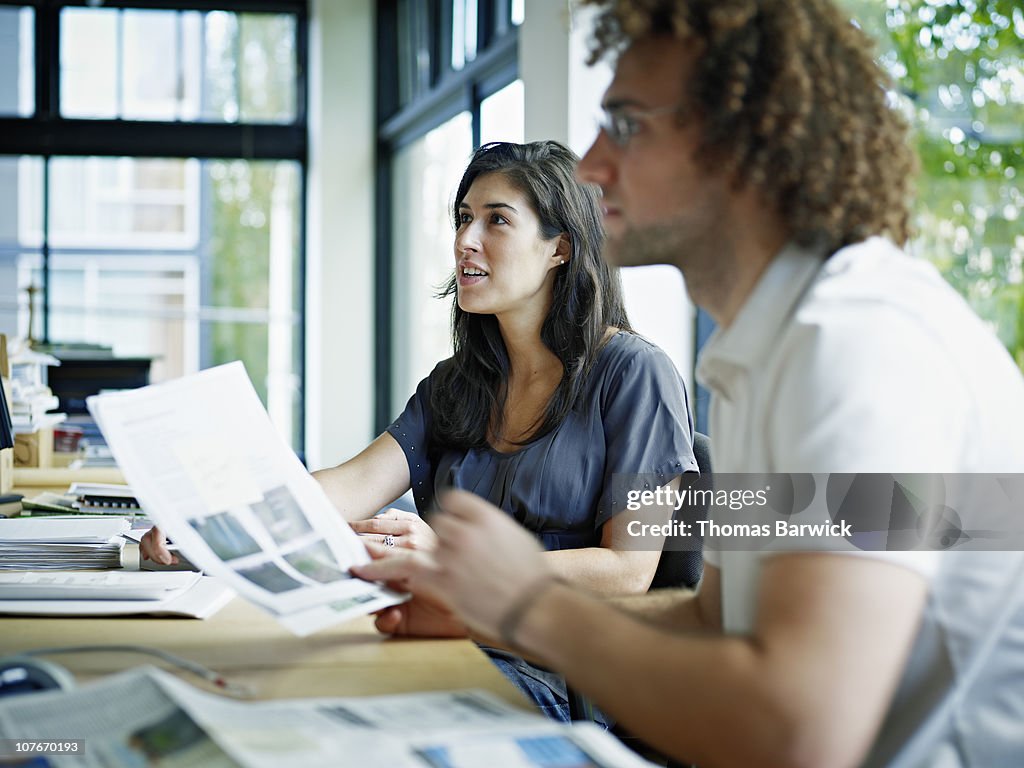 Coworkers listening at desk in office
