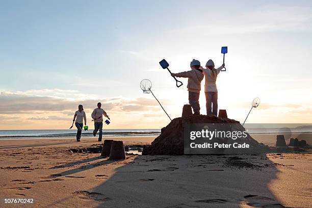 family on beach in winter - sand castle stock pictures, royalty-free photos & images