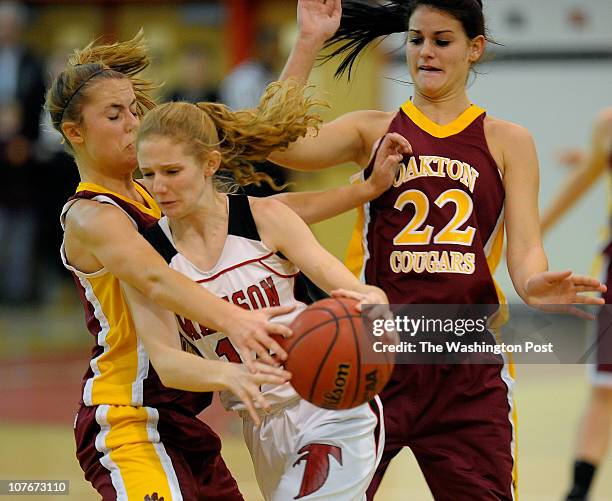 Oakton's CAroline Coyer, left, fouls Madison's Katie Kerrigan, center, with Oakton's Halley Cummins standing by as Oakton defeats Madison 57 - 46 in...