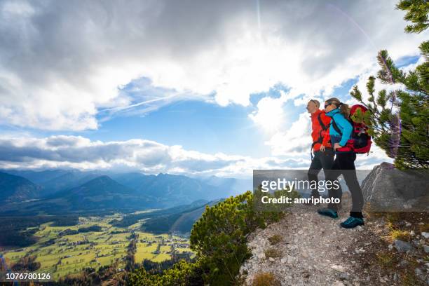 sportieve bergbeklimmer paar passen op oogpunt in bergen - eisberg stockfoto's en -beelden