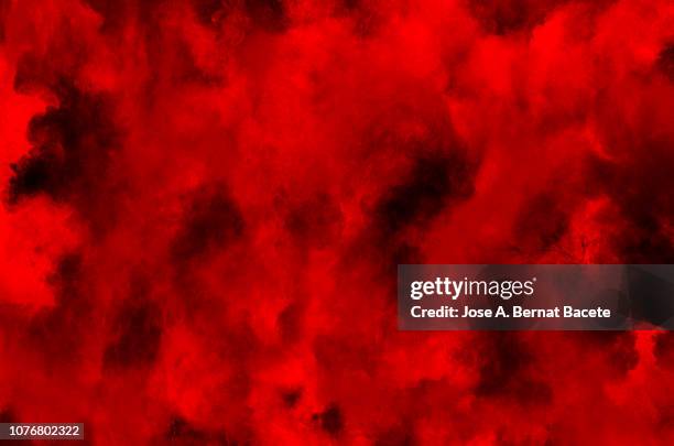 explosion by an impact of a cloud of particles of powder and smoke of color red and black background. - fire black background stock pictures, royalty-free photos & images
