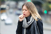 Illness young woman coughing in the street.