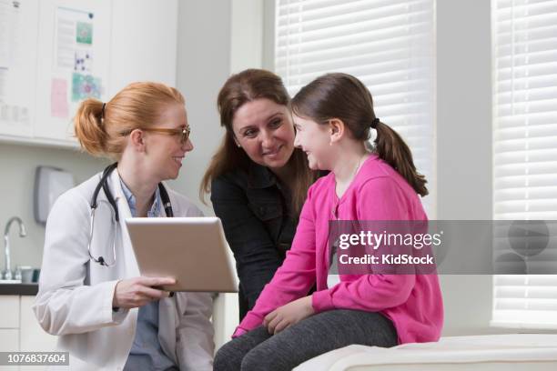 female doctor discussing medical exam with patient using digital tablet - kidstock girl stock pictures, royalty-free photos & images