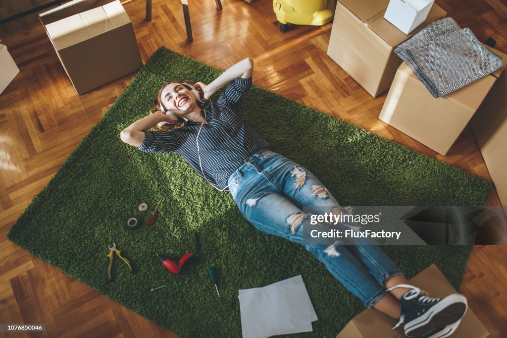 Vrolijk meisje genieten van muziek terwijl het uitpakken in een nieuwe appartement