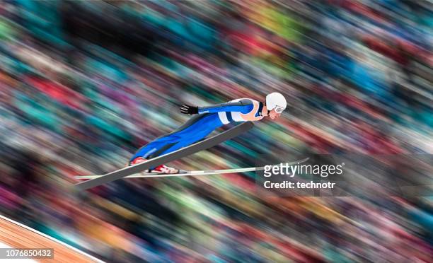 side view of male ski jumper in mid-air against blurred background - salto de esqui imagens e fotografias de stock