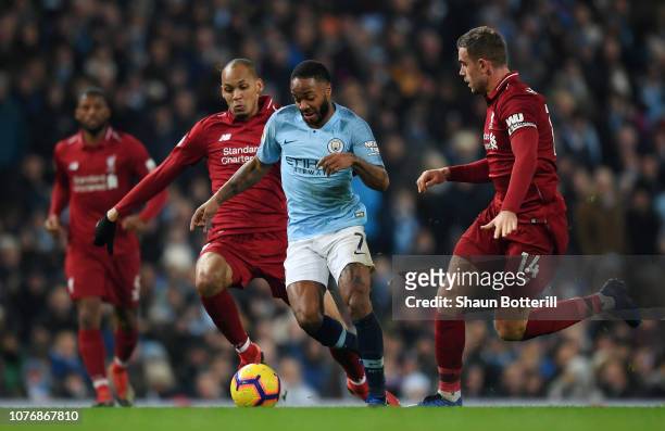 Raheem Sterling of Manchester City is challenged by Fabinho of Liverpool and Jordan Henderson of Liverpool during the Premier League match between...