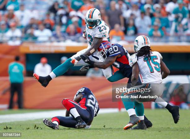 Ronnie Brown of the Miami Dolphins runs with the ball over Leodis McKelvin while being tackled by Donte Whitner of the Buffalo Bills on December 19,...