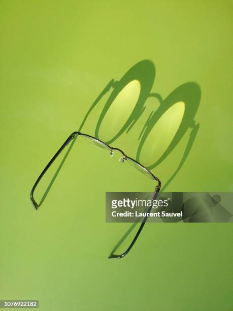 funny close-up of black round glasses with shadow against green background - laurent sauvel photos et images de collection