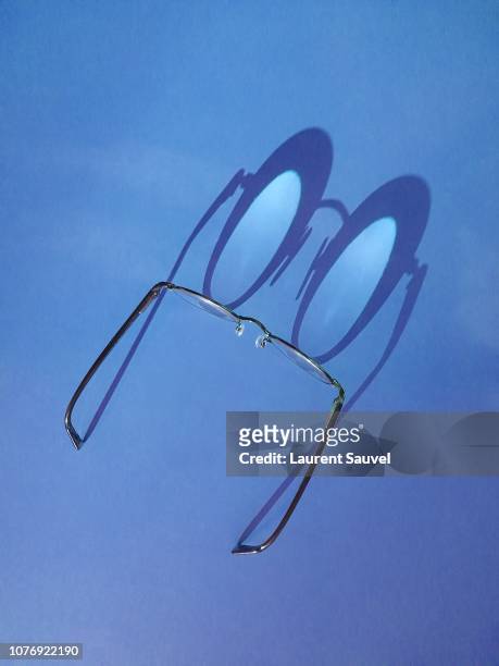 funny close-up of black round glasses with shadow against blue background - laurent sauvel photos et images de collection