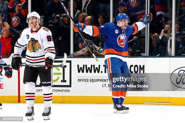 Devon Toews of the New York Islanders celebrates his game winning goal during overtime to give his team a 3-2 win as Patrick Kane of the Chicago...