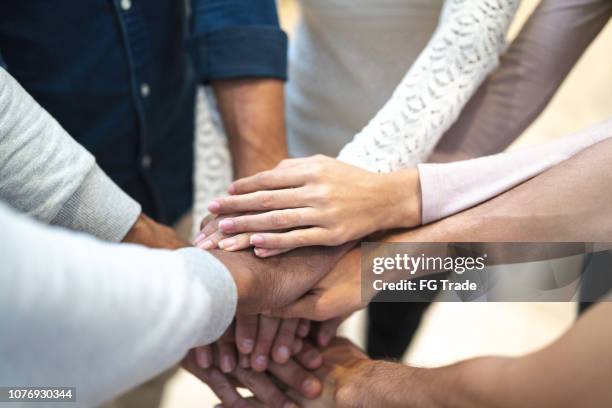 socios poniendo sus manos encima de la otra en el lugar de trabajo - hands clasped fotografías e imágenes de stock