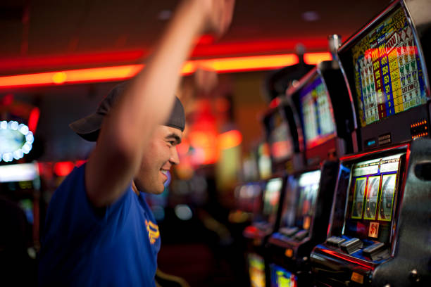 cheering native american man playing slot machines in casino - casino stock pictures, royalty-free photos & images