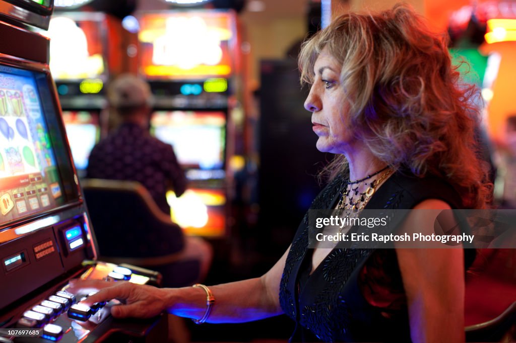 Caucasian woman playing slot machine in casino