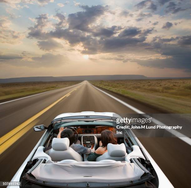 couple driving convertible through remote area - car road sunset fotografías e imágenes de stock