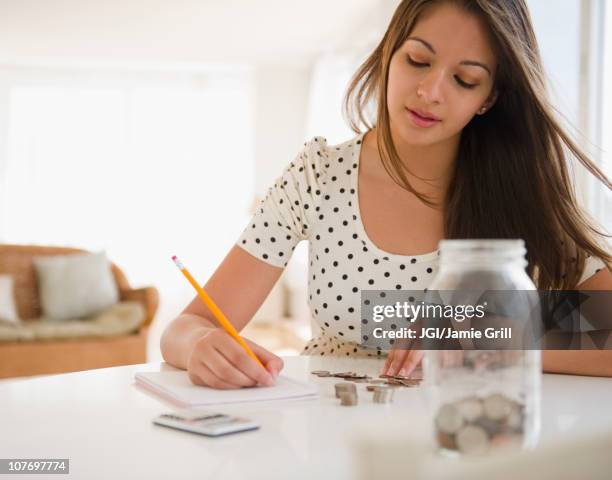 indian woman counting coins and writing on notepad - gierig stockfoto's en -beelden