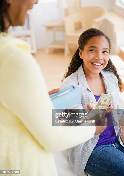 mother handing money to daughter - pocket money stock pictures, royalty-free photos & images