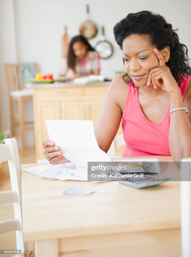 Black mother looking at monthly bills