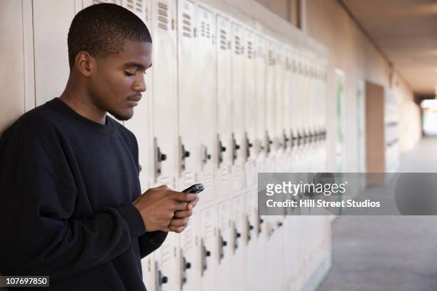 african american high school student using cell phone near lockers - 少年　横顔 ストックフォトと画像