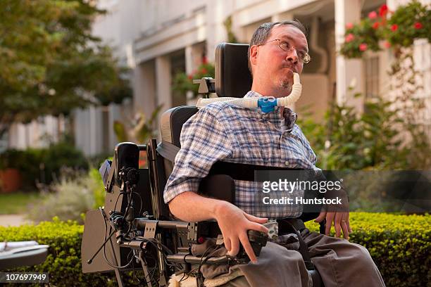 man with duchenne muscular dystrophy sitting in a motorized wheelchair using power controller with degenerated hands - motorized wheelchair stock pictures, royalty-free photos & images
