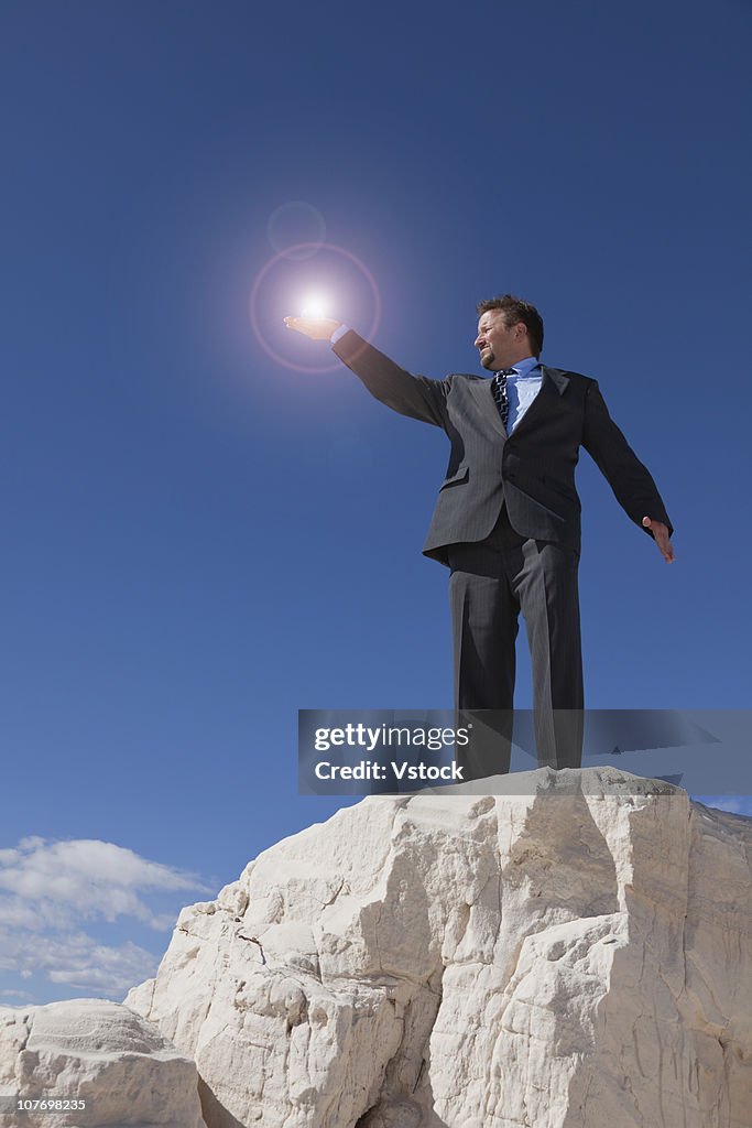 USA, New Mexico, White Sands National Monument, Businessman holding glowing orb on rock