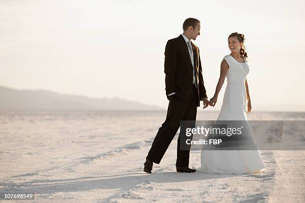 usa, utah, boneville salt flats, bride and groom holding hands in desert - utah wedding stock pictures, royalty-free photos & images