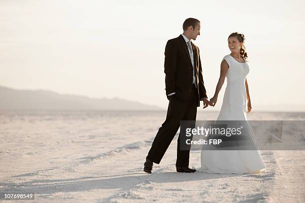 usa, utah, boneville salt flats, bride and groom holding hands in desert - utah wedding imagens e fotografias de stock