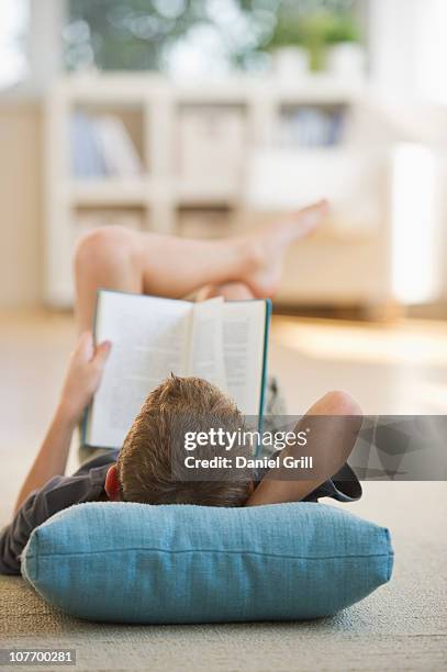 usa, new jersey, jersey city, boy (10-11) lying on floor and reading book - boy 10 11 stock pictures, royalty-free photos & images