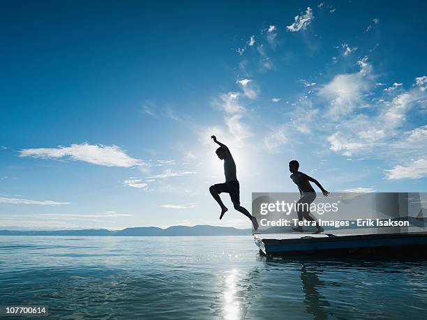 usa, utah, garden city, boys (10-11,12-13) jumping from raft - jumping into lake stock-fotos und bilder