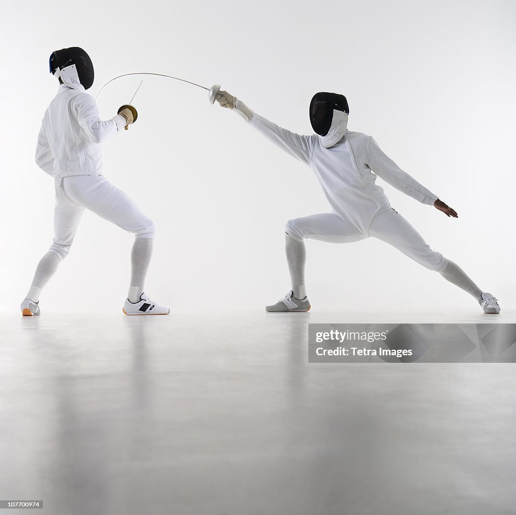 Studio shot of fencers in attacking lunge