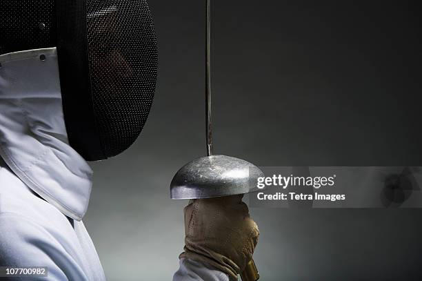 studio portrait of fencer holding fencing foil - face guard sport stock-fotos und bilder