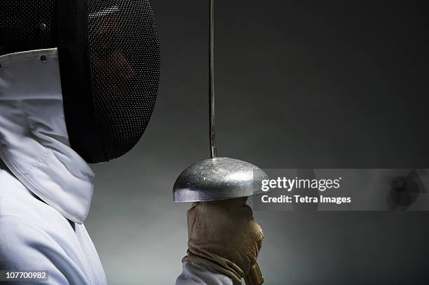 studio portrait of fencer holding fencing foil - fencing imagens e fotografias de stock