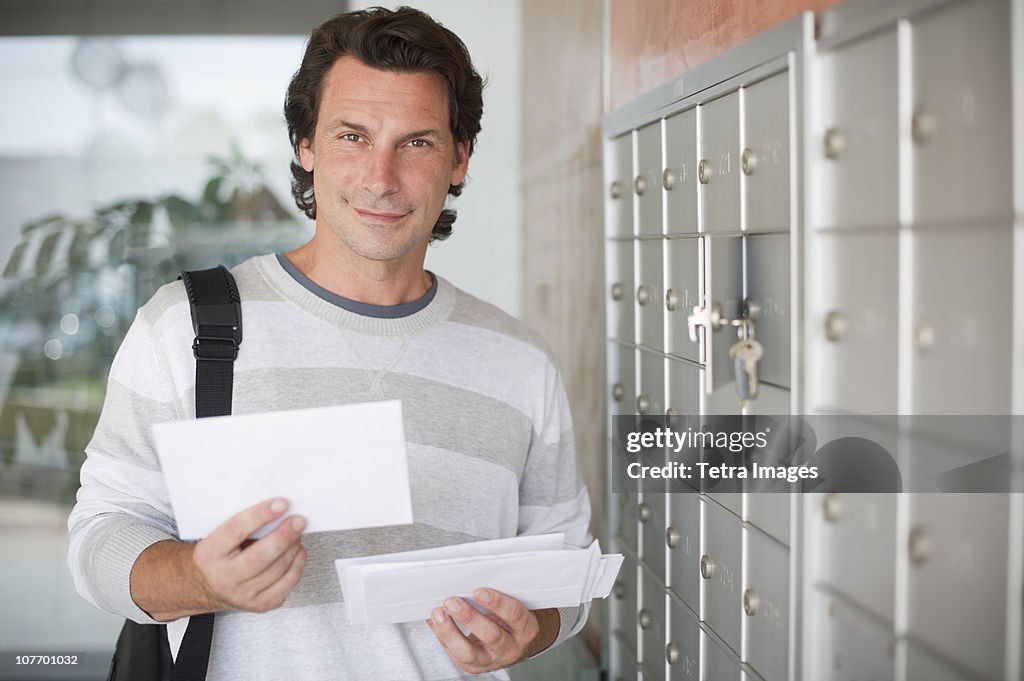 USA, New Jersey, Man standing next to mailboxes and holding letters