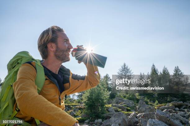 hiker male drinking on mountain trail from water bottle - gourd stock pictures, royalty-free photos & images