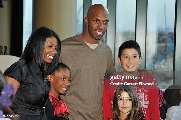 Chauncey Billups of the Denver Nuggets and his wife Piper Billups pose for a photo with a family from the Warren Village during a Holiday Party on...