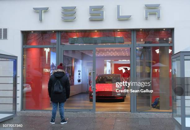 Man satnds outside a Tesla dealership on January 4, 2019 in Berlin, Germany. Tesla is expected to soon begin deliveries of the Model 3 in Europe even...