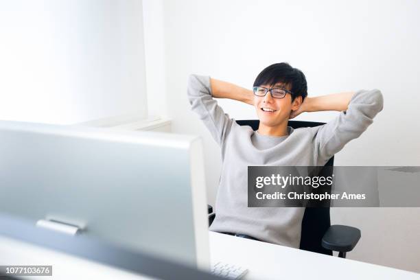 young professional man using computer - hands behind head stock pictures, royalty-free photos & images