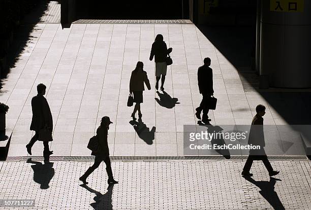 silhouettes of office employees going to work. - a buisness man with a brifecase stock-fotos und bilder